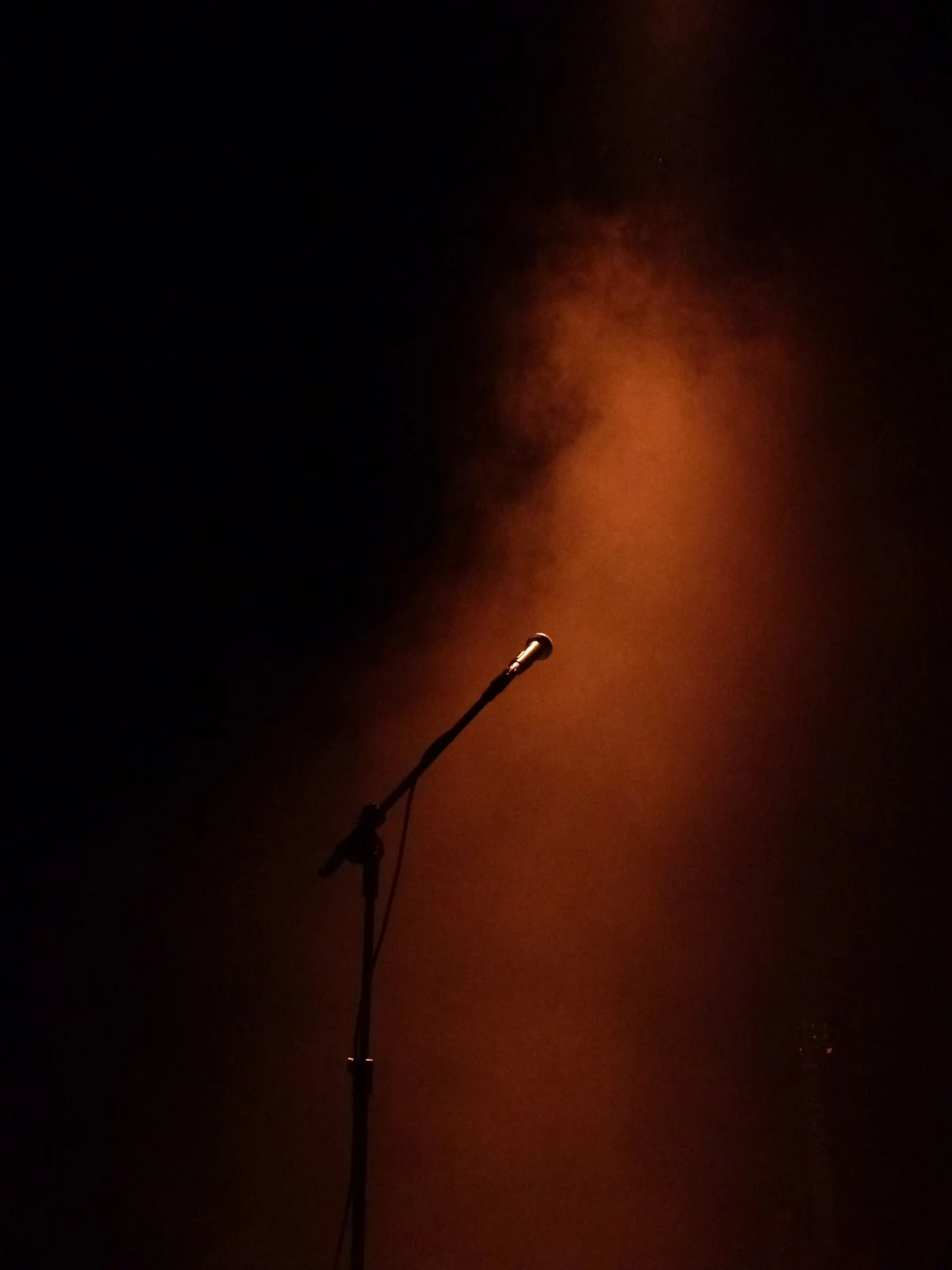 Microphone under warm stage lighting, illustrative stock image